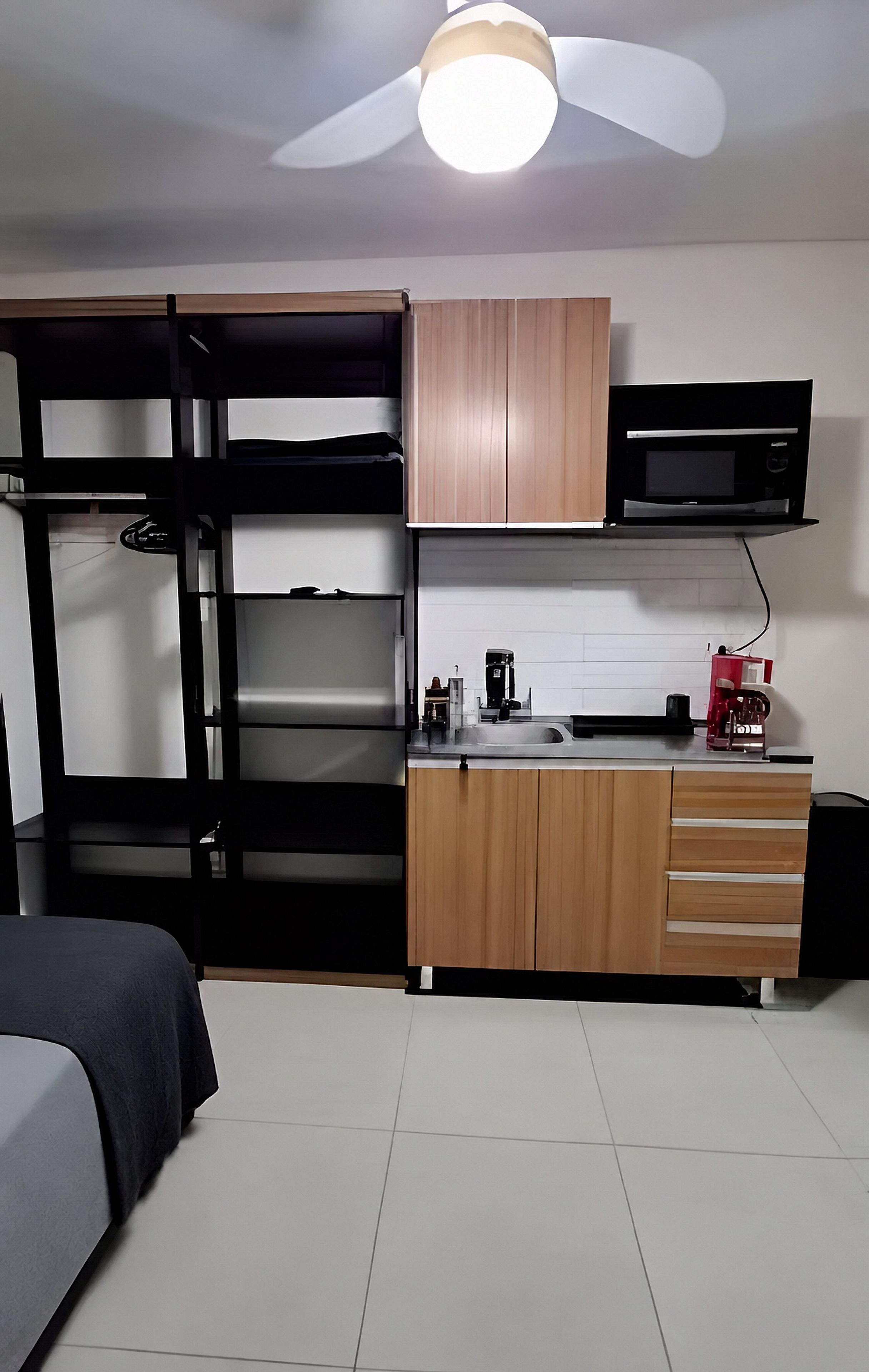A compact room with bunk beds, a kitchenette, and a ceiling fan.