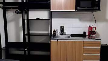 A compact room with bunk beds, a kitchenette, and a ceiling fan.