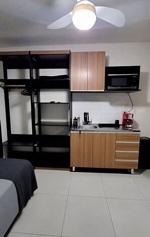 A compact room with bunk beds, a kitchenette, and a ceiling fan. - Salles Residence Barra Funda (São Paulo)