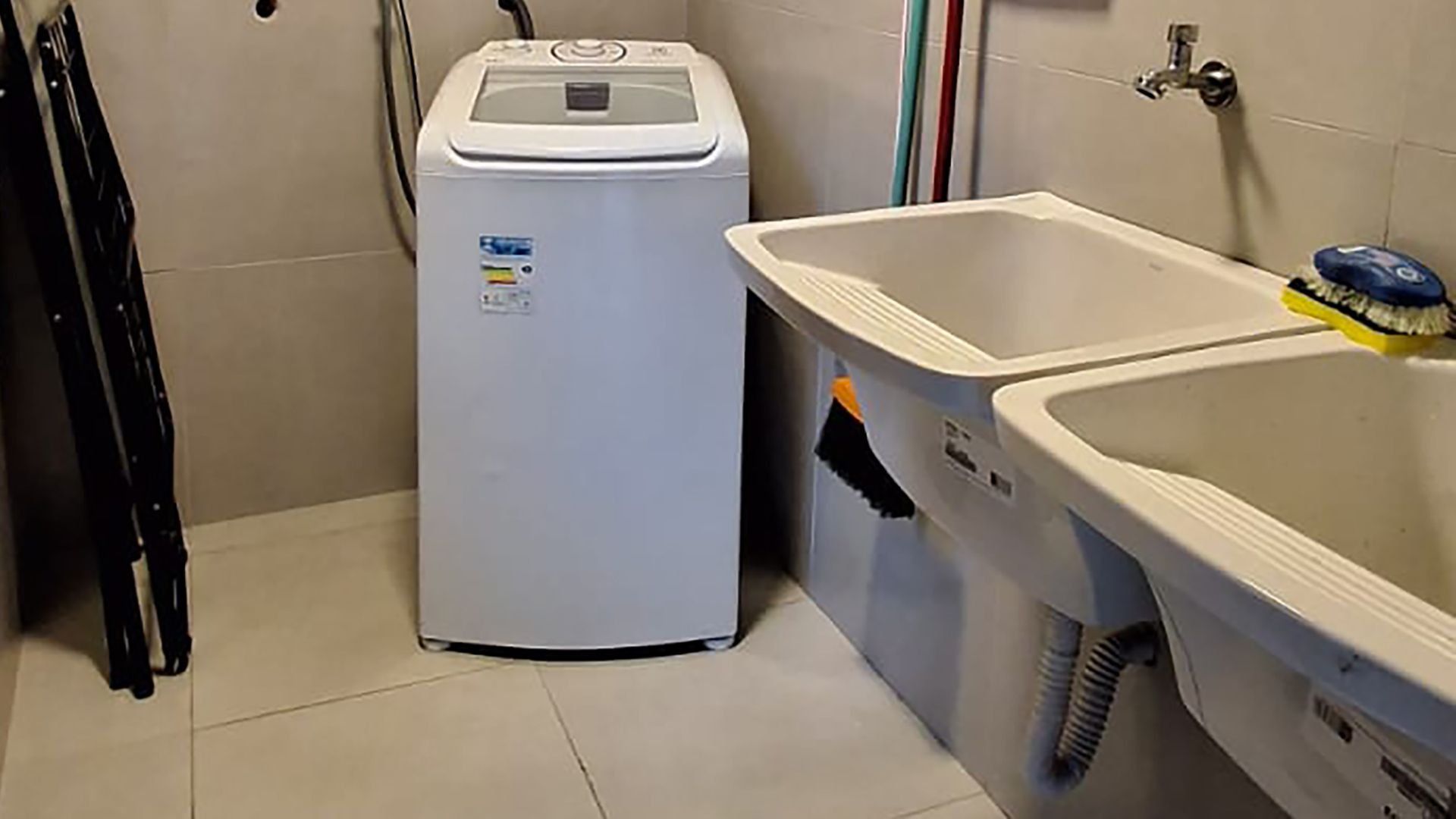 Ein kleiner Raum mit Waschmaschine, Spüle und Bürste sowie einer Leiter.