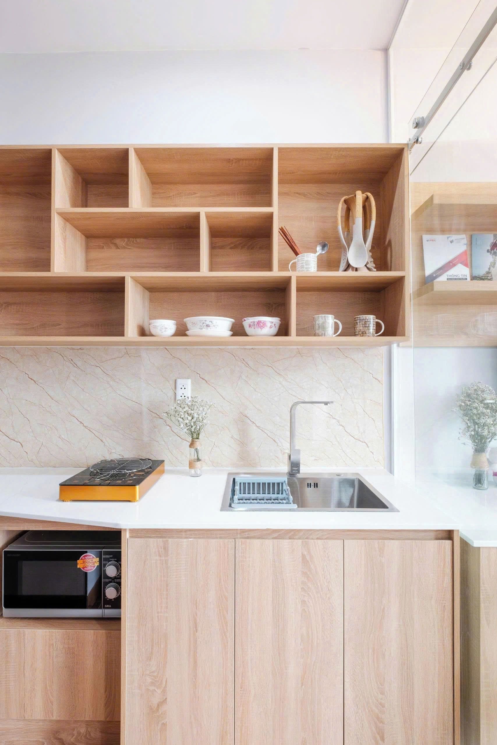 Une cuisine moderne avec des meubles en bois, un four à micro-ondes encastré et un évier en acier inoxydable.
