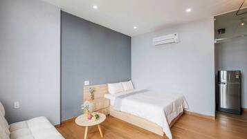 A modern bedroom with a bed, bedside table, and a small round table with flowers.