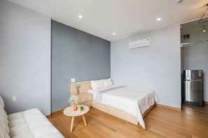 A modern bedroom with a bed, bedside table, and a small round table with flowers. - TMH HOUSE 03 LVT Hotel & Apartment (Son Tra)