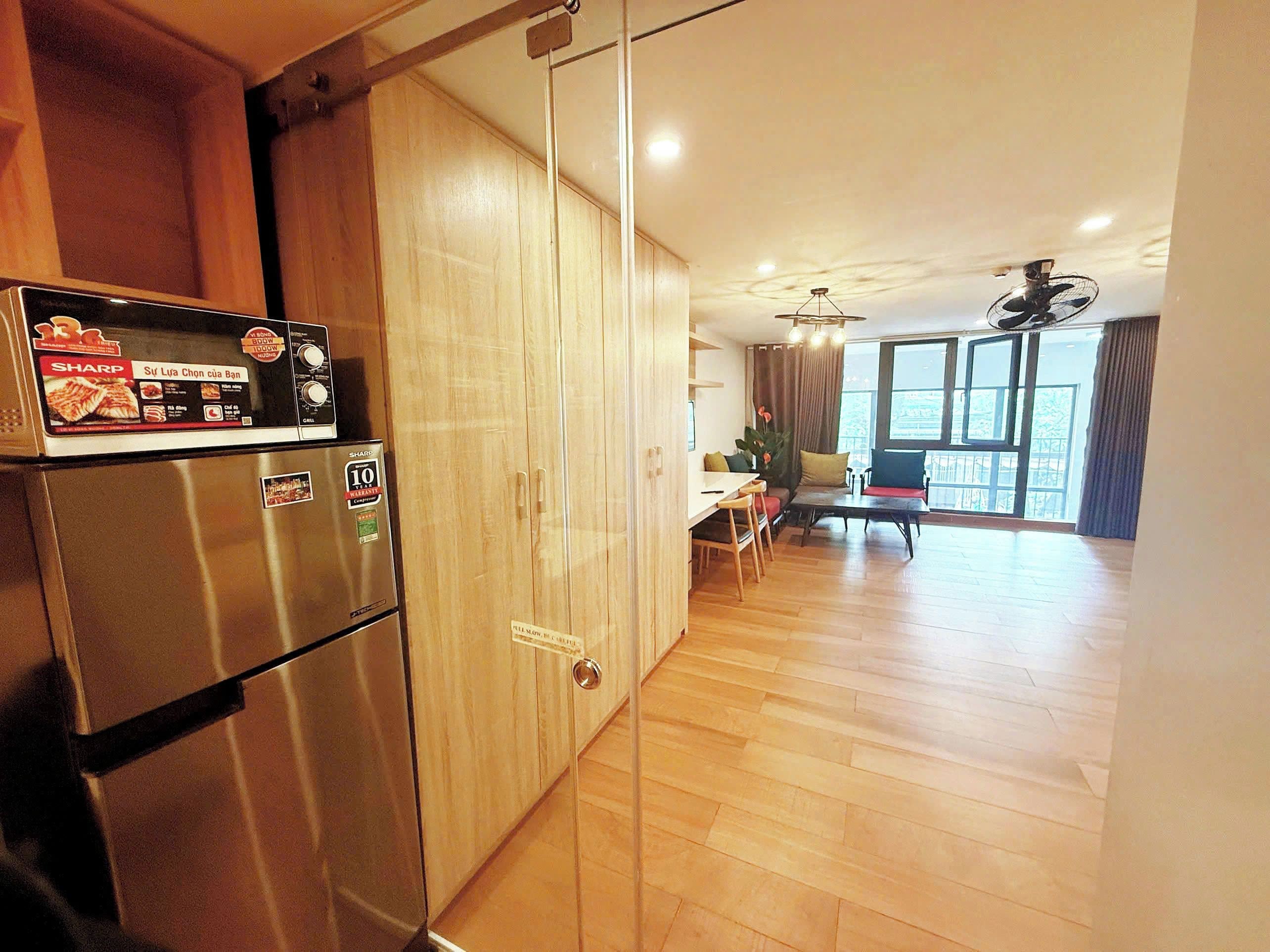 A kitchen with a stainless steel refrigerator, wooden cabinets, and a dining area with a table and chairs.