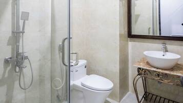 A modern bathroom with a glass-enclosed shower, a toilet, and a vanity with a sink and mirror.