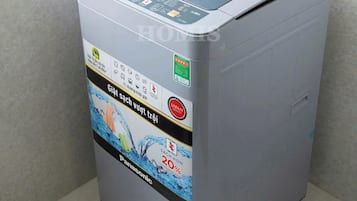 A gray water purifier with a transparent water tank, control panel, and a water inlet hose.