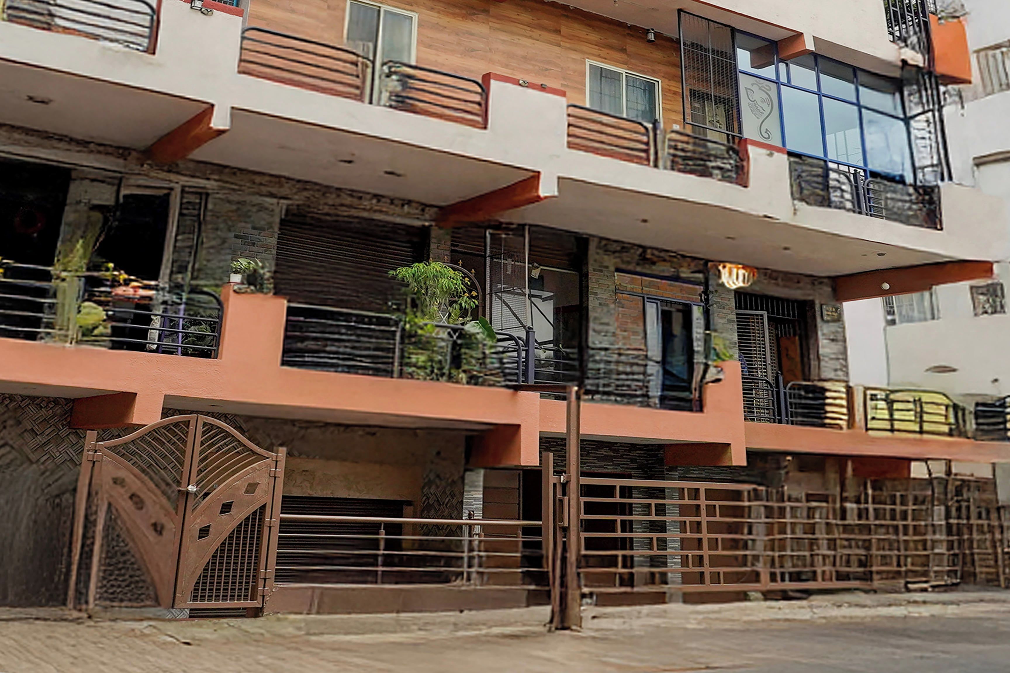 Edifício residencial com vários andares, varandas, entrada com portão e fachada que combina tijolos e elementos modernos.