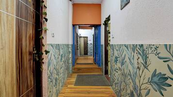 Un pasillo con paredes de diseño, piso de madera y una puerta con un letrero de número.