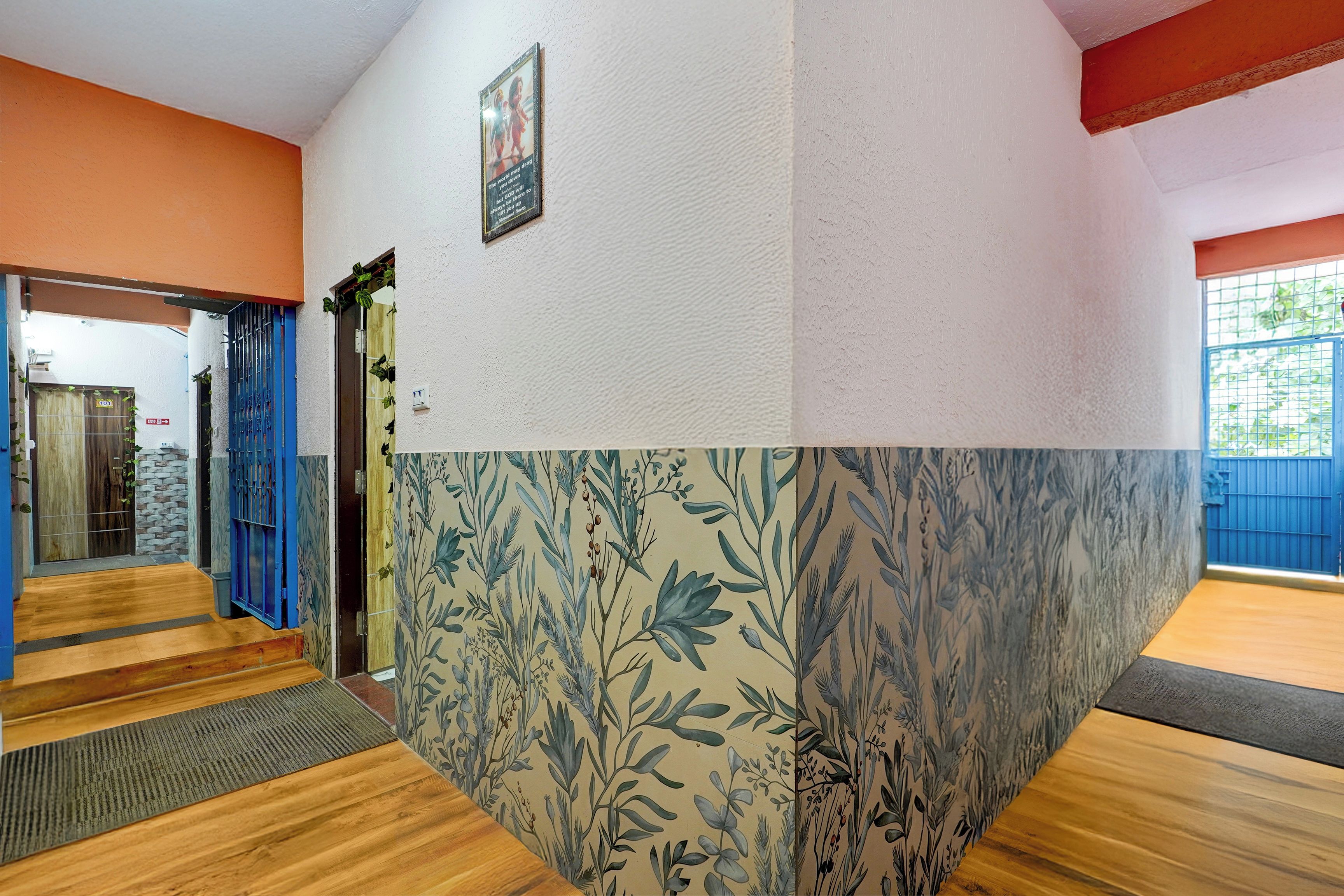 A hallway with a wooden floor, a blue gate, and a door with a sign.