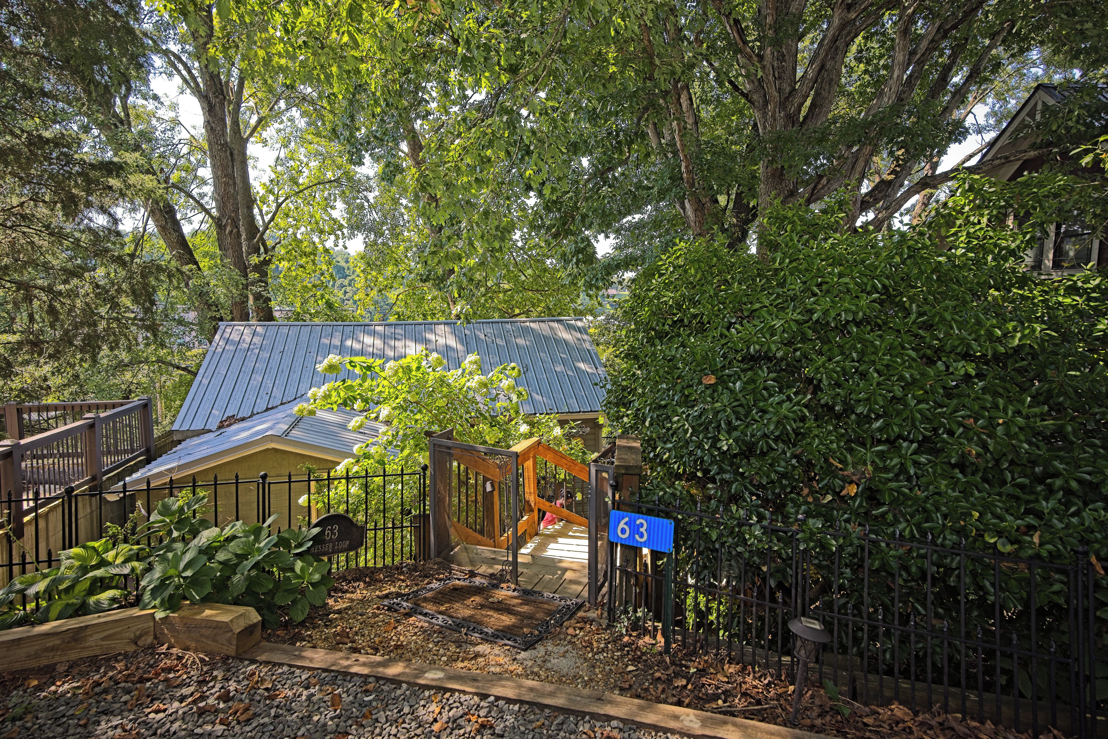 A residential property with a metal gate, a wooden fence, and a house with a blue roof.