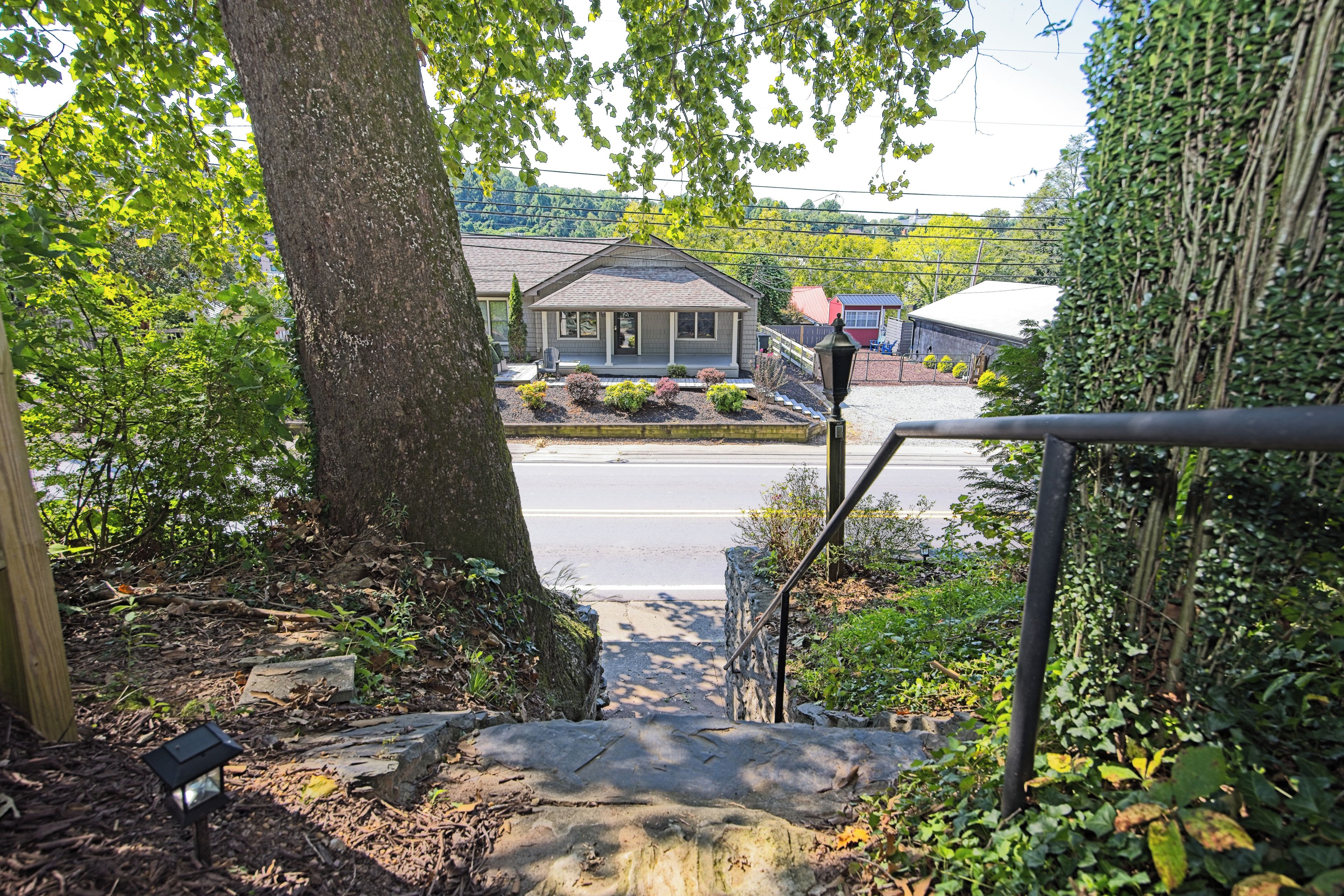 A residential property with a front yard, a staircase leading to a porch, and a view of the street.