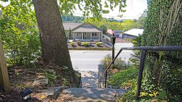 A residential property with a front yard, a staircase leading to a porch, and a view of the street.