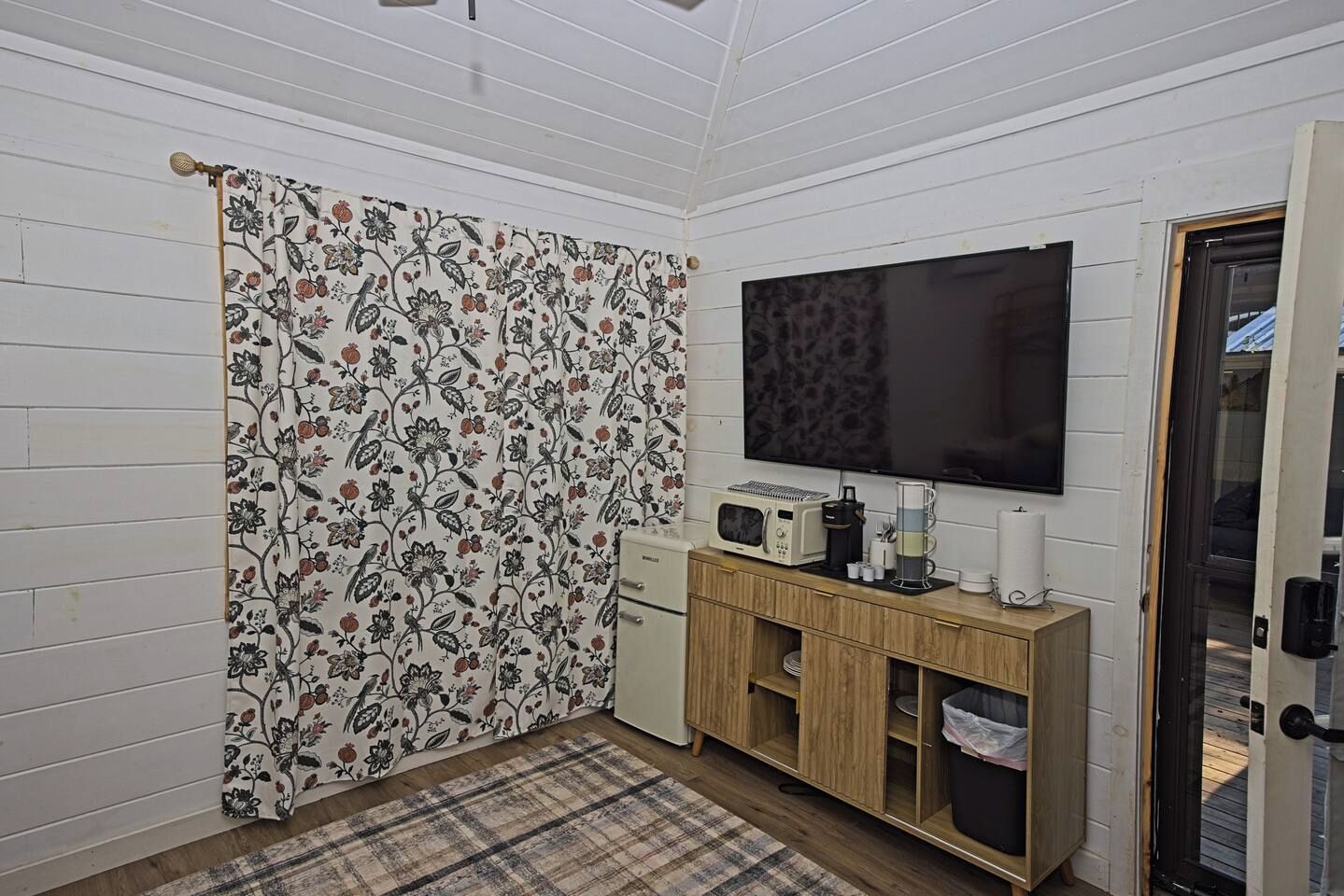 A small room with a television, a microwave, a coffee maker, and a cabinet.