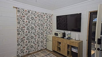 A small room with a television, a microwave, a coffee maker, and a cabinet.