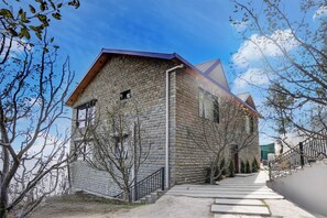 Um edifício de pedra de dois andares, com fachada de tijolo e telhado de metal, e uma escadaria que leva à entrada.