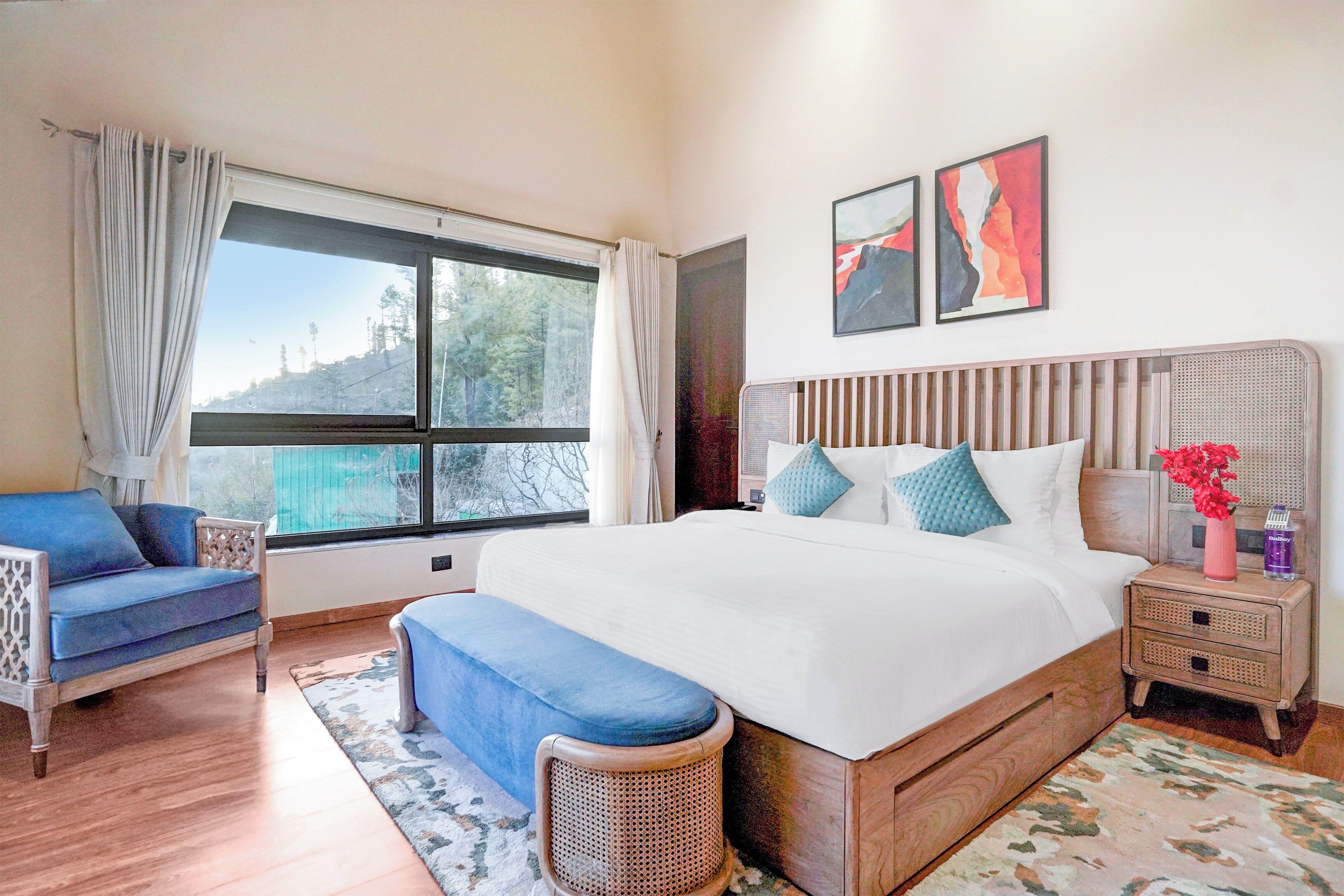 A bedroom with a large bed, a chair, a bedside table, and a window with curtains.