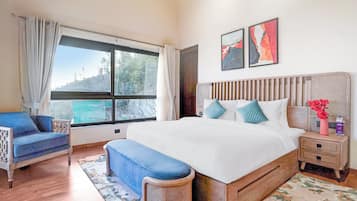 A bedroom with a large bed, a chair, a bedside table, and a window with curtains.