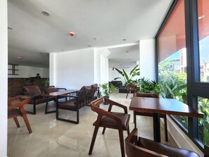 A modern indoor space with seating arrangements, a reception area, and a view through large windows. - Viet Apartments (Da Nang)