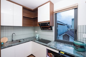 A modern kitchen with a built-in oven, a kettle, and a rice cooker on the countertop. - Viet Apartments (Da Nang)