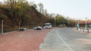 A paved road with a brick sidewalk, a white bus, and a motorcycle parked on the side.