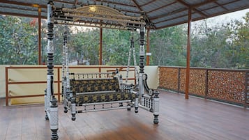 A four-poster bed with intricate black and white patterns, a bench with floral upholstery, and a wooden floor.