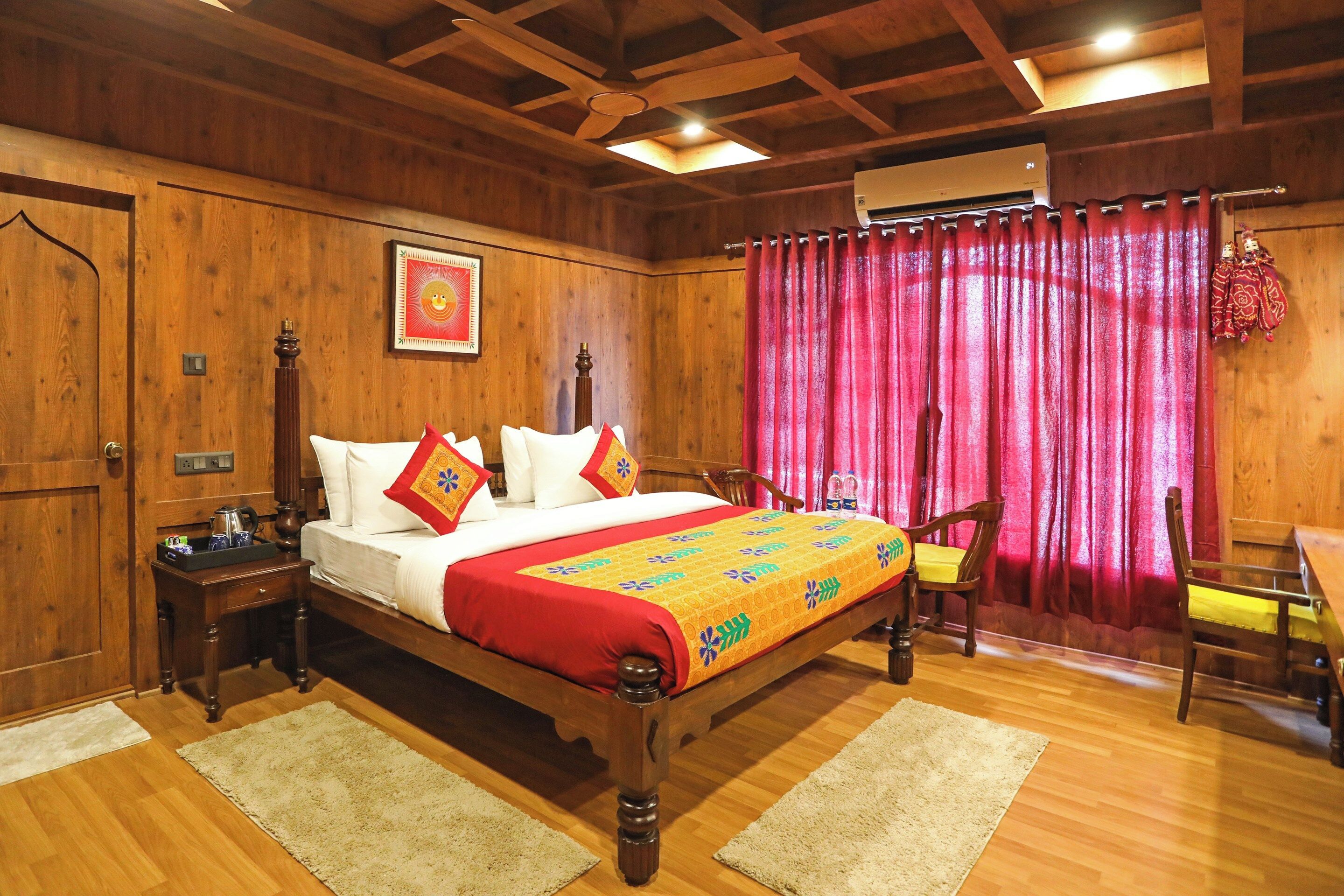 Quarto de madeira com cama, mesa de cabeceira, cadeira e janela com cortinas.