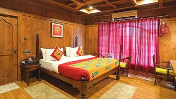 Quarto de madeira com cama, mesa de cabeceira, cadeira e janela com cortinas.