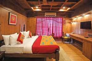A wooden room with a bed, a desk, and a TV.