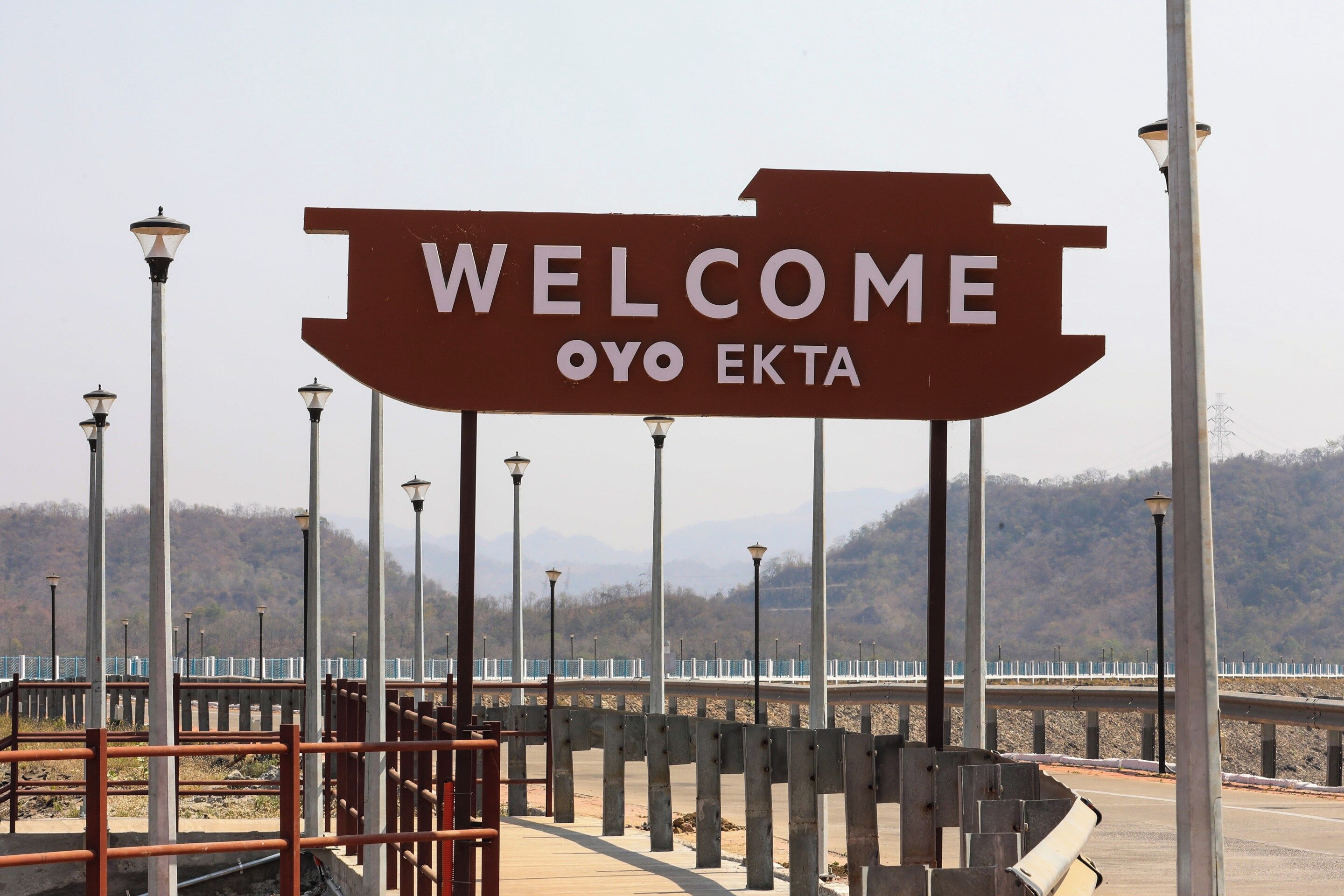 Un letrero grande de bienvenida con el texto 'WELCOME OYO EKTA' colocado en una estructura metálica.