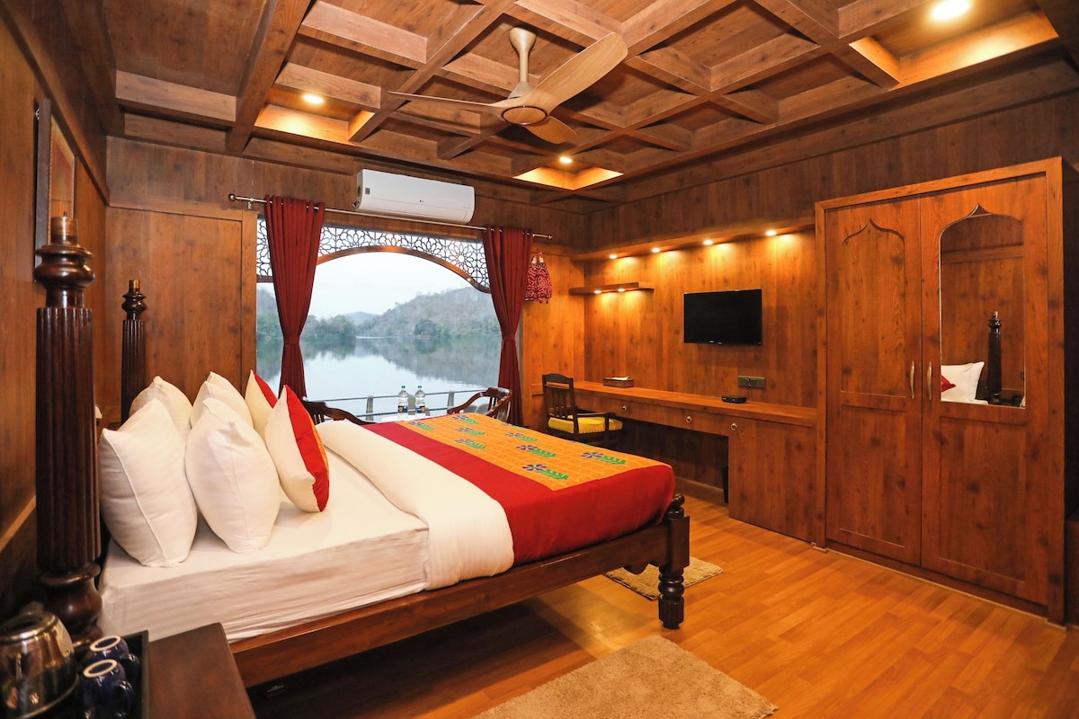 A wooden room with a bed, a desk, a television, and a wardrobe.