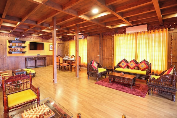 A cozy room with wooden furniture, a chessboard, and a television.