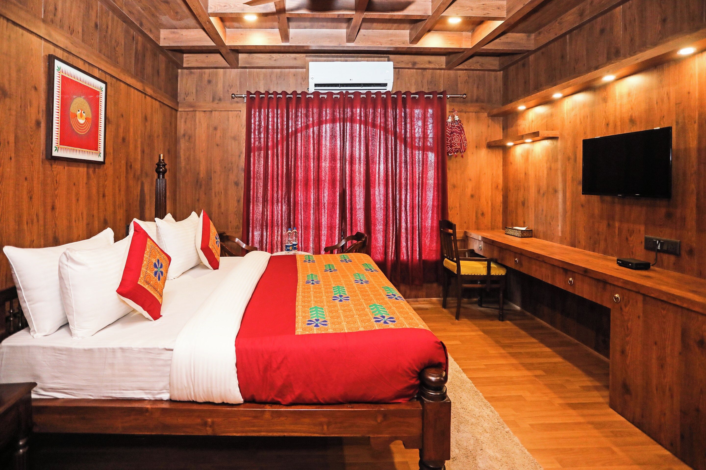 A wooden-themed bedroom with a bed, a desk, and a TV.
