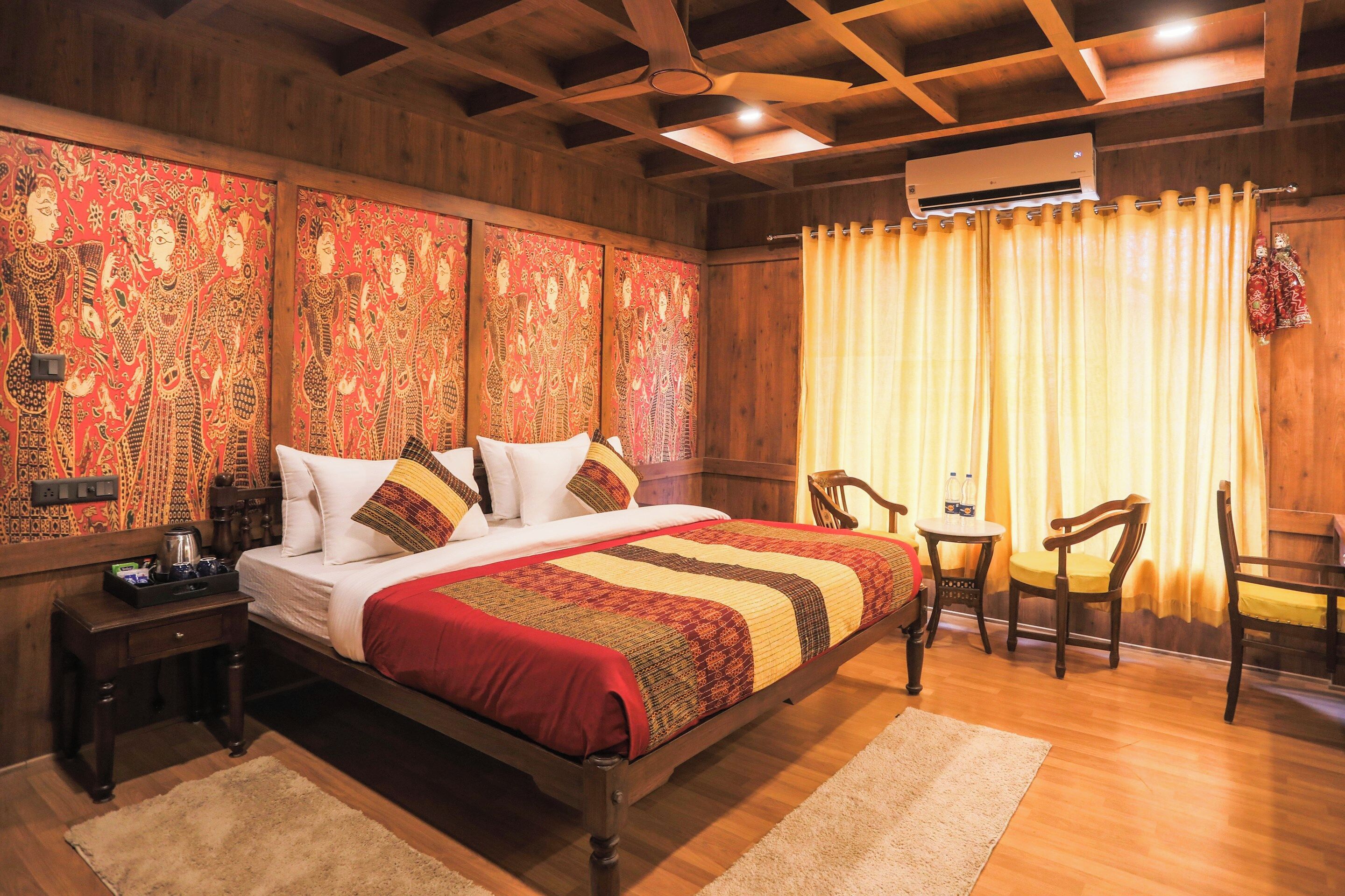 A wooden-paneled bedroom with a bed, a small table with chairs, and an air conditioning unit.