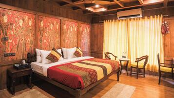 A wooden-paneled bedroom with a bed, a small table with chairs, and an air conditioning unit.