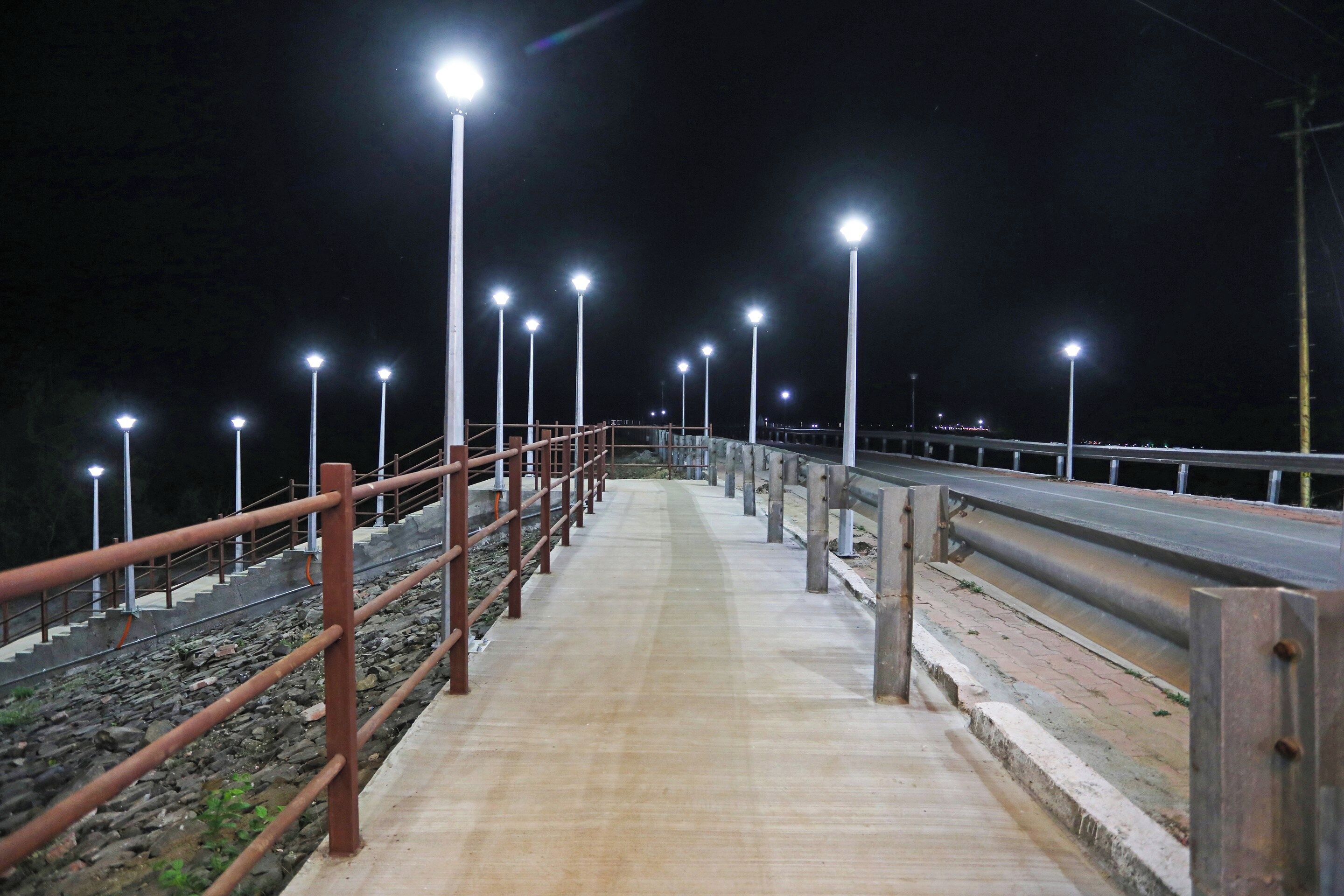 Une promenade nocturne dotée de garde-corps en métal et d’un éclairage public régulièrement espacé.