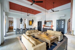 A spacious living room with a large sectional sofa, a coffee table, and a dining area with a long table and chairs. - House of Jasol by DanCenter, Jaipur (Jaipur)