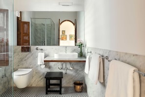 A bathroom with a marble floor, a white sink, a toilet, a small wooden stool, and a mirror above the sink. - House of Jasol by DanCenter, Jaipur (Jaipur)