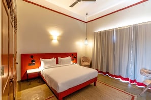 A hotel room with a bed, nightstand, chair, and a window with curtains. - House of Jasol by DanCenter, Jaipur (Jaipur)