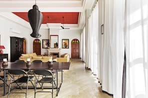 A spacious living room with a high ceiling, a fireplace, and a dining area with a table and chairs. - House of Jasol by DanCenter, Jaipur (Jaipur)
