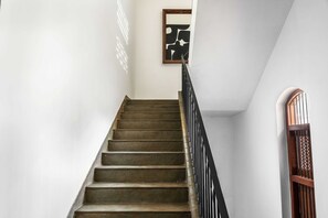A staircase with a wooden handrail and a black metal railing, leading to a landing with a framed artwork. - House of Jasol by DanCenter, Jaipur (Jaipur)