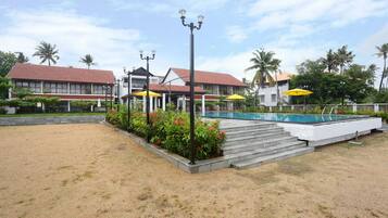 A hotel with a swimming pool, outdoor seating, and a garden area.