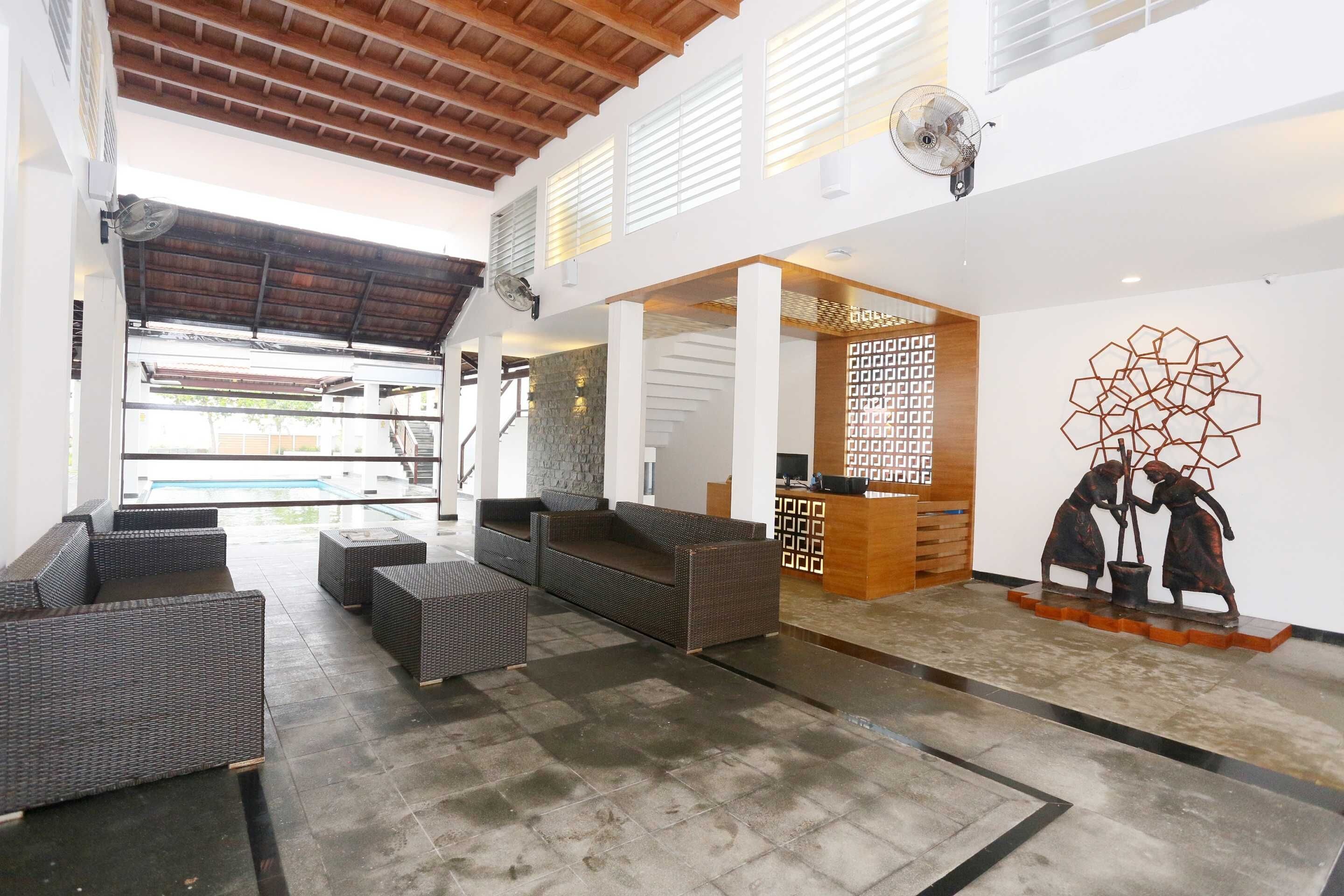 Un amplio vestíbulo con vista a la piscina, muebles de mimbre y un mostrador de recepción.