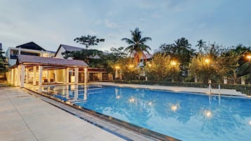 A swimming pool with a sunken seating area and a covered pavilion.