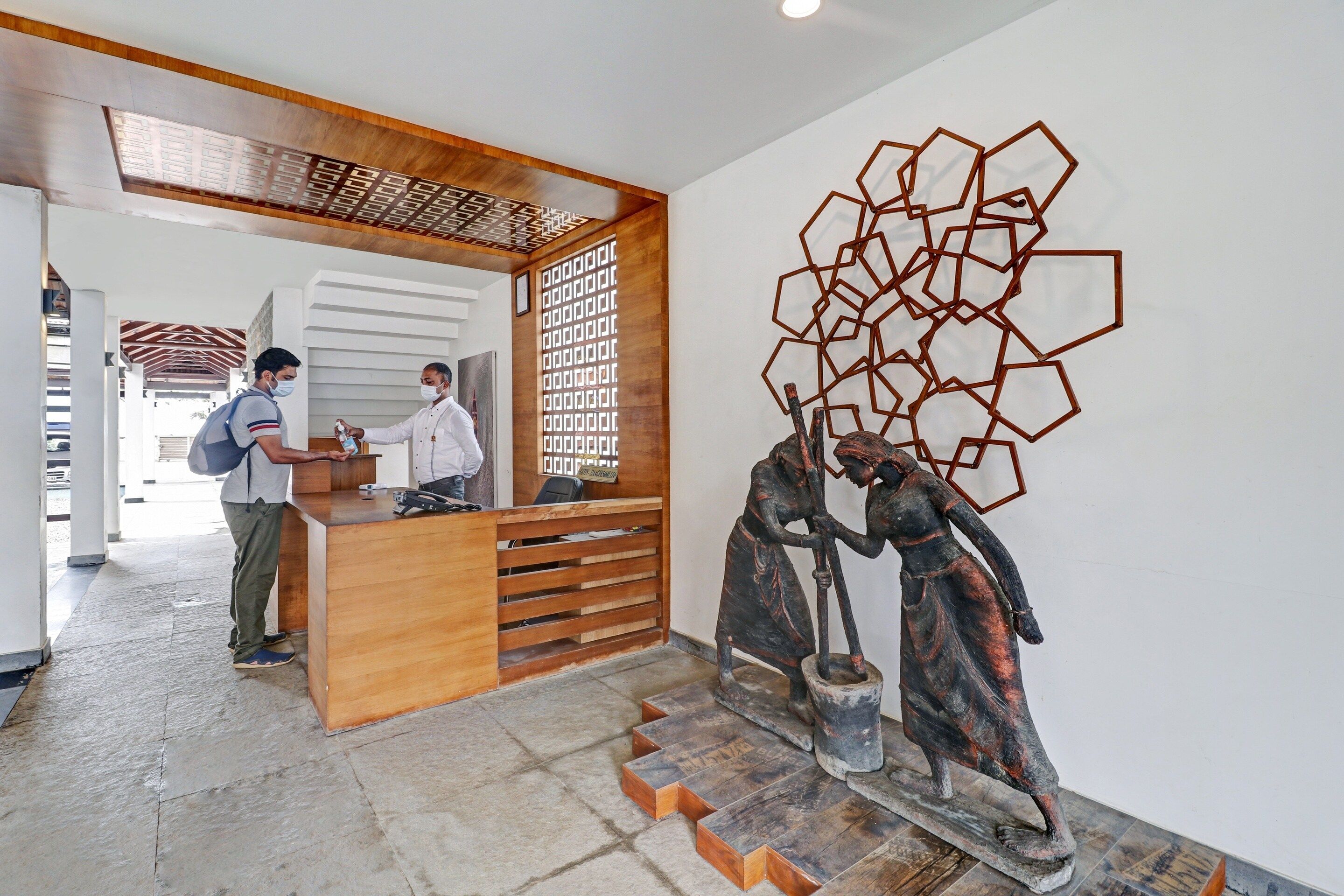 A reception desk with a wooden counter and a modern geometric wall art piece.