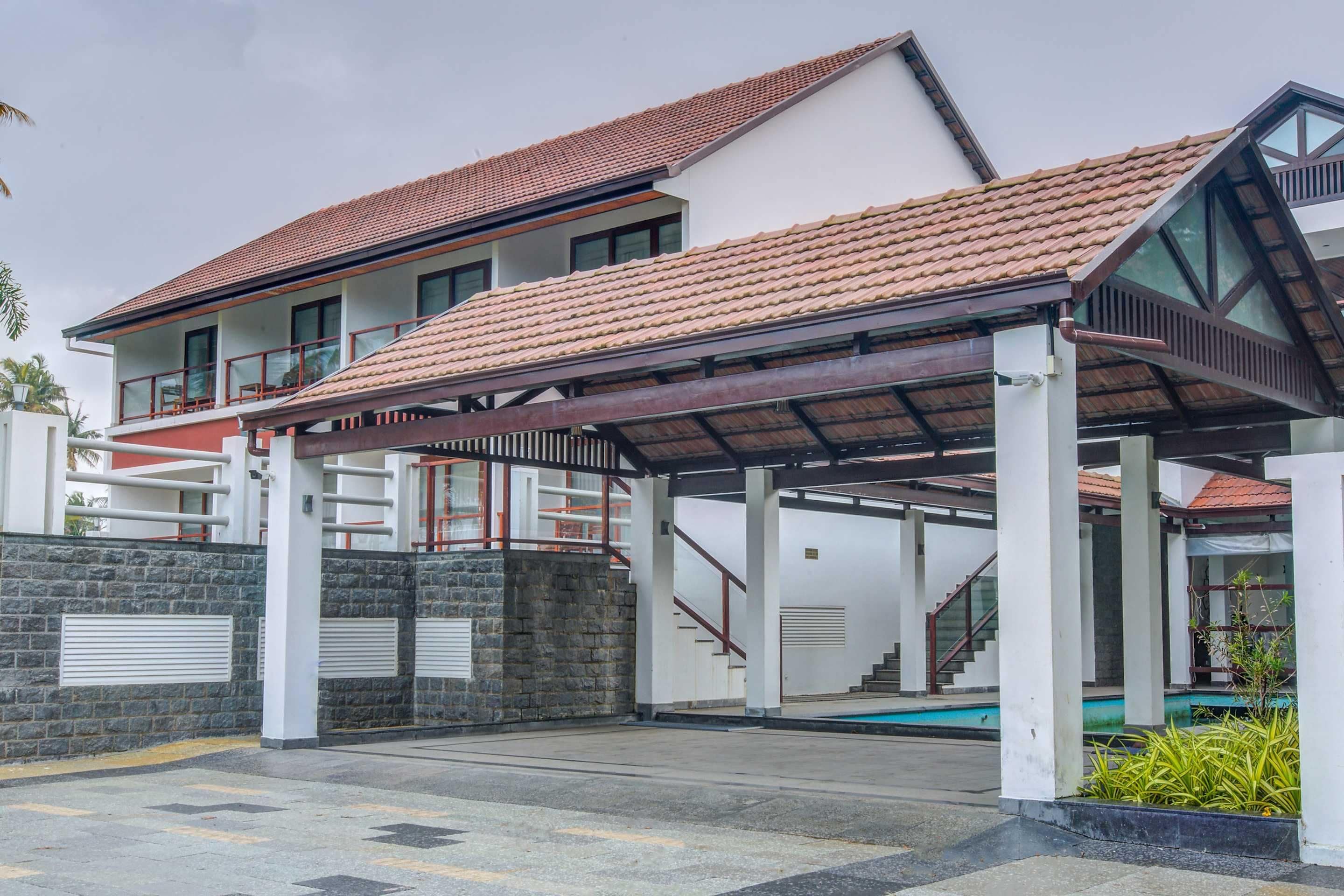 A two-story house with a covered patio, a swimming pool, and a stone wall.