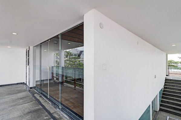 A modern interior with a glass door leading to an outdoor area, a staircase, and a visible outdoor view.