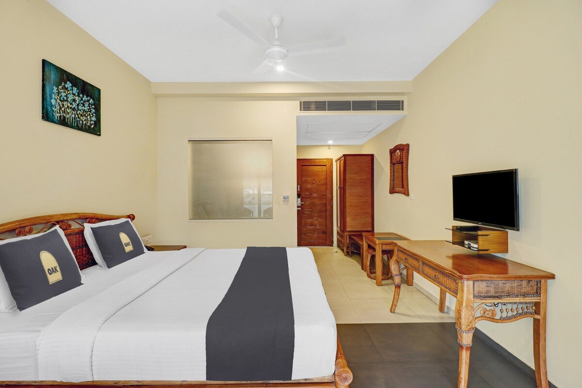 Habitación de hotel con cama, escritorio, televisor y un cuadro en la pared.