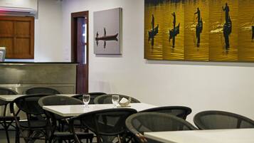Interior de restaurante con mesas, sillas y obras de arte en las paredes.
