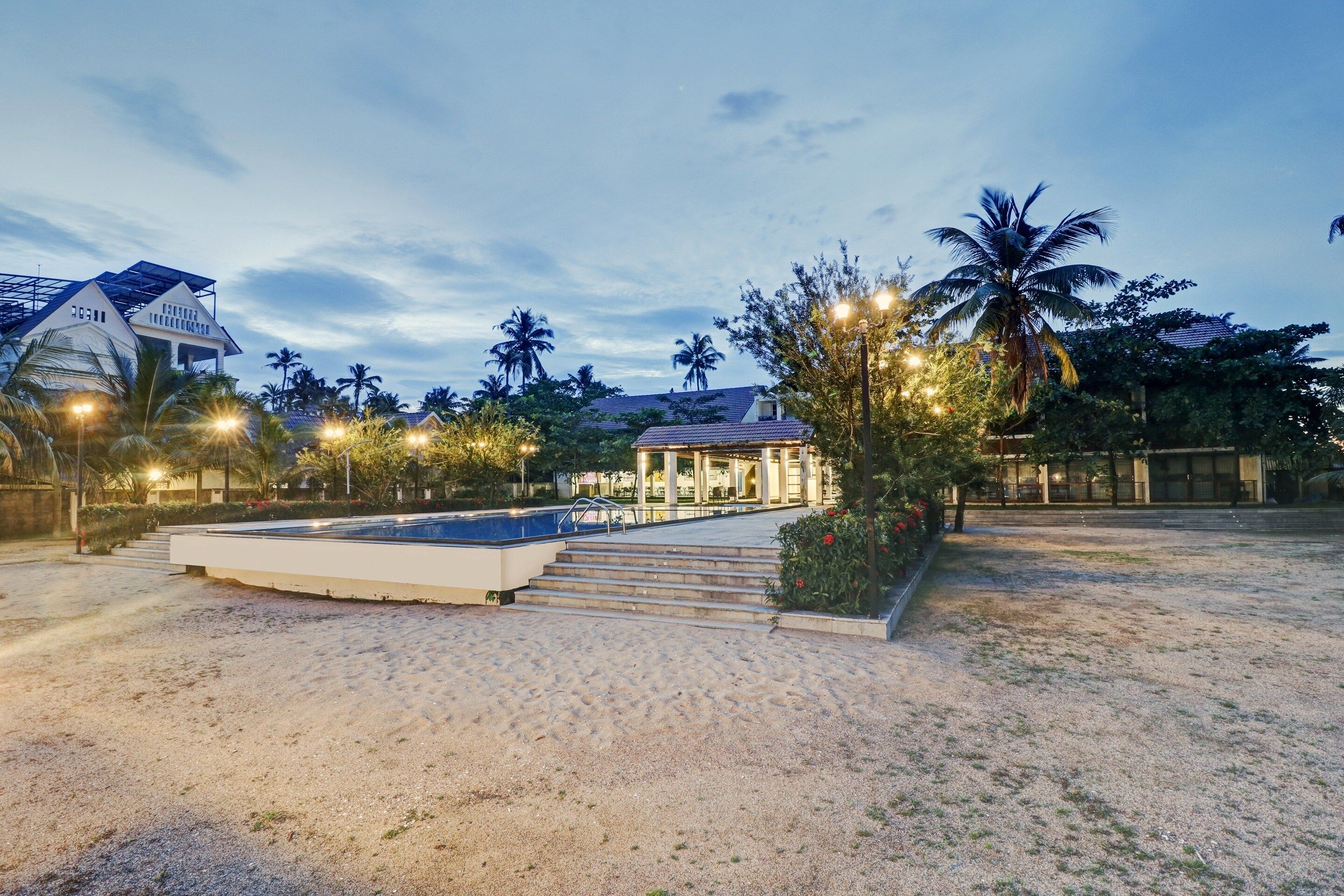 A resort with a pool, palm trees, and a building with a tiled roof.