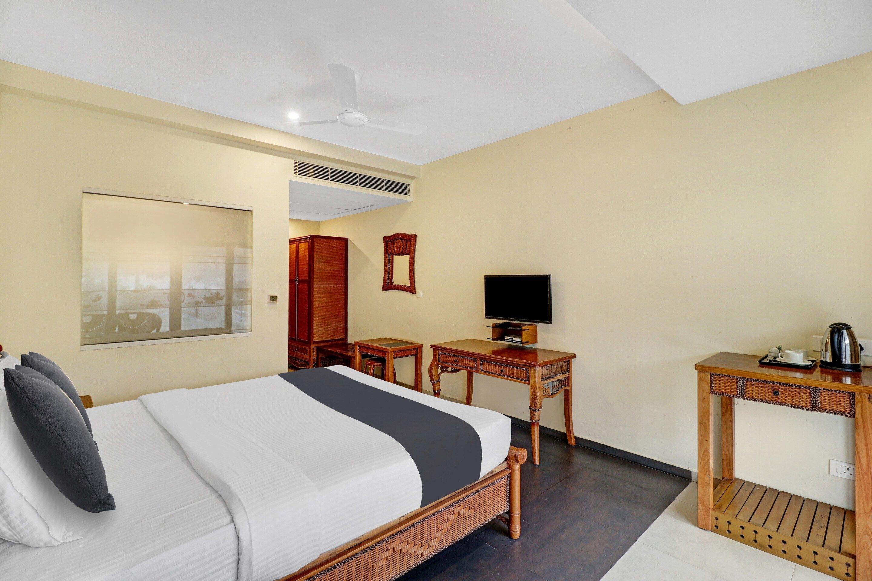 A hotel room with a bed, a television, a desk, and a mirror.